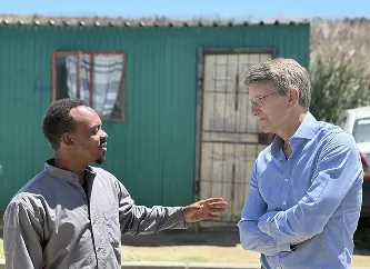 Two adults speaking outdoors beside a building
