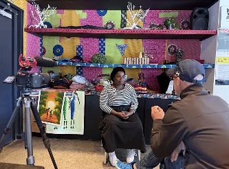 Camera recording a seated conversation in a colourful room