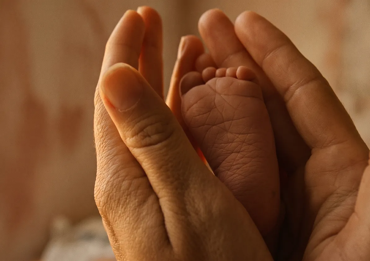 Concept illustration: Adult hands holding a baby's feet